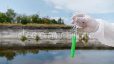 穿着防护服的人的手显示了一个试管，其中分析了来自污染河流或湖泊的水